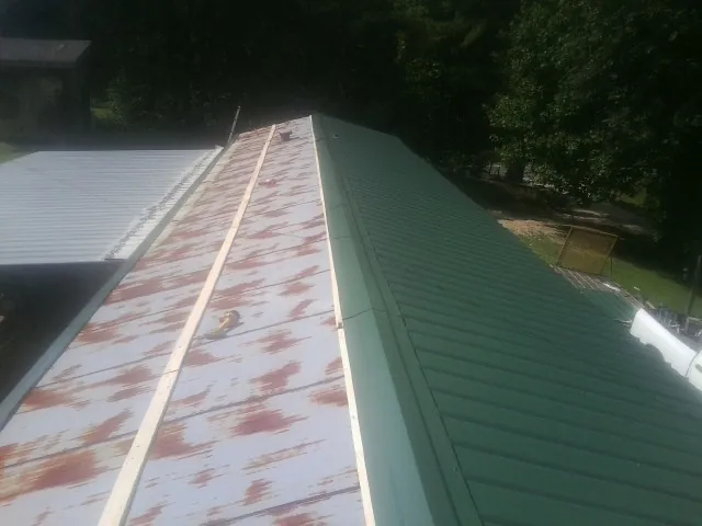 Old rusted panels beside newly installed green metal roofing — Wind Damage Roof Repair by Roofing Brothers in Norristown