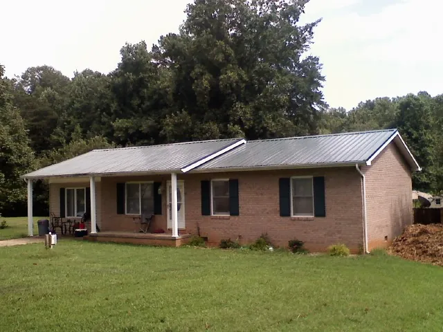 Gray metal roof on a brick ranch house with a side carport in Norristown