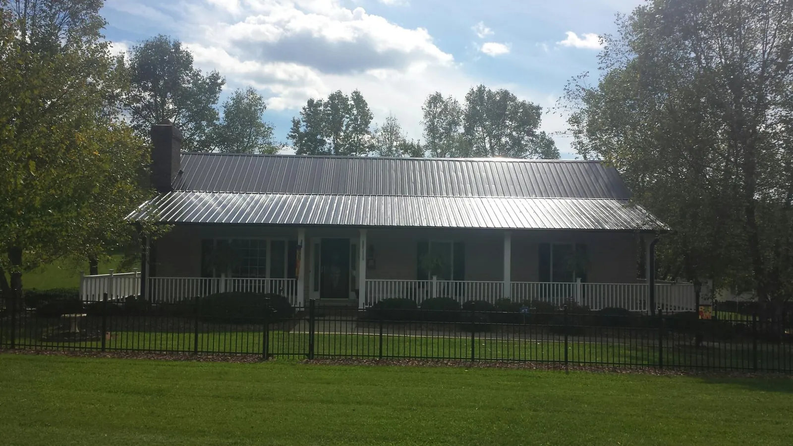 Gray metal roof on a brick ranch with a full width front porch — Gutter Guard Installation work by our crew in Norristown