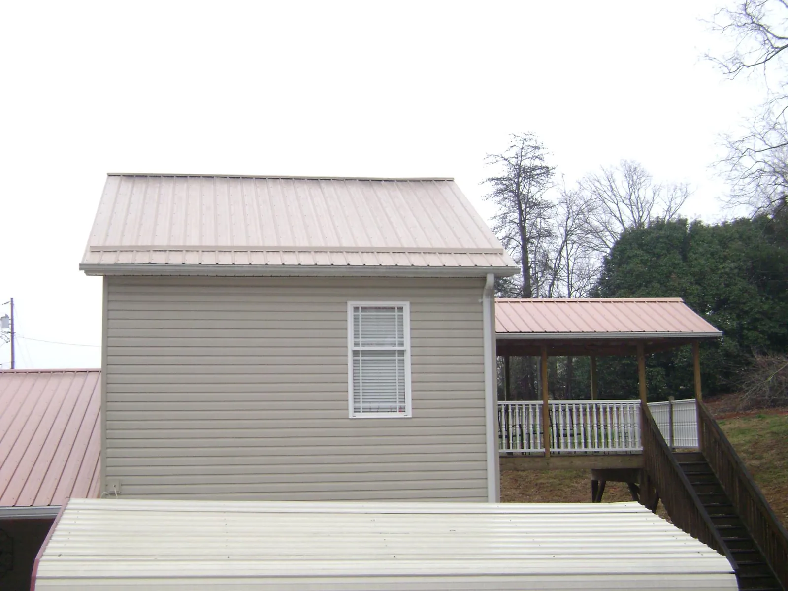 Tan metal roofs on a two story addition and attached porch, from a Roof Replacement job in Norristown