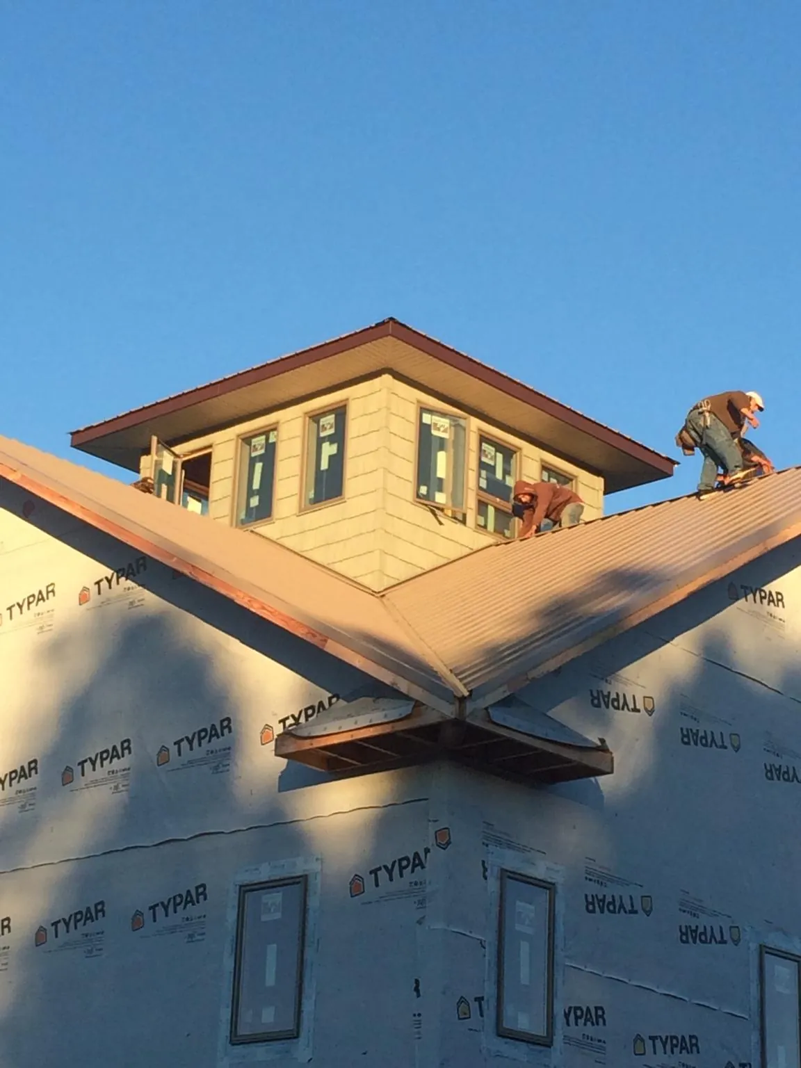 Roofers working around a rooftop cupola on a new metal roof at sunset — Roof Waterproofing in Norristown by Roofing Brothers